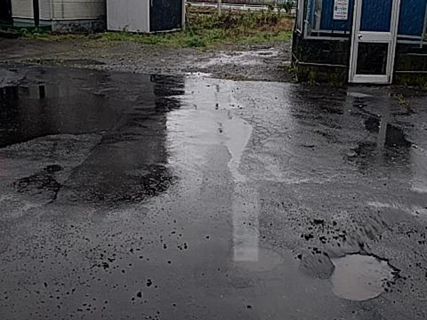濡れた路面で、右下の穴と、左の黒く濡れた部分の2か所が赤い枠で囲まれている