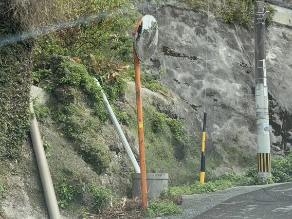 A curve mirror on an orange post on the left slope of a hill road